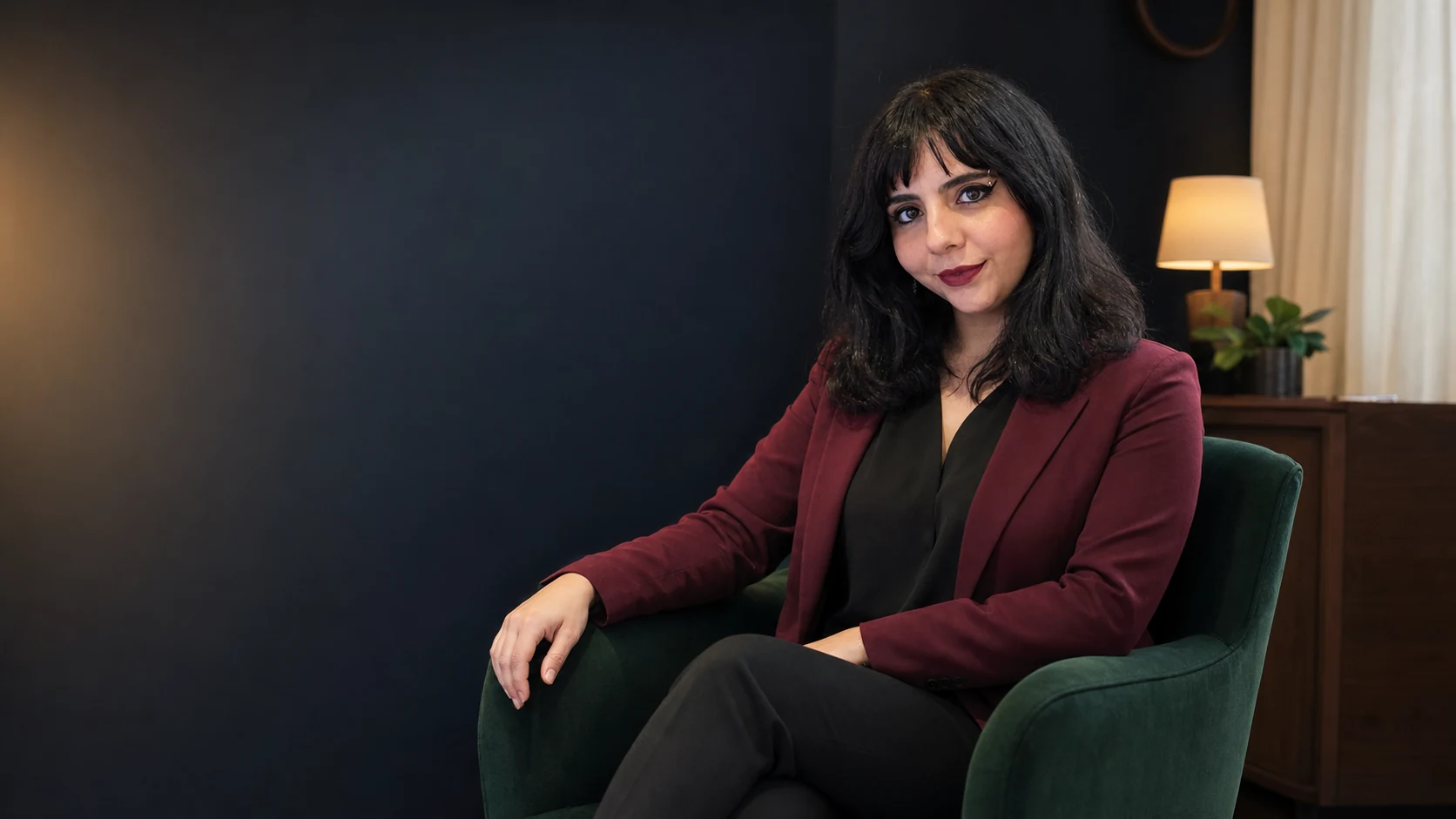 Daniela sentada em uma poltrona verde no consultório